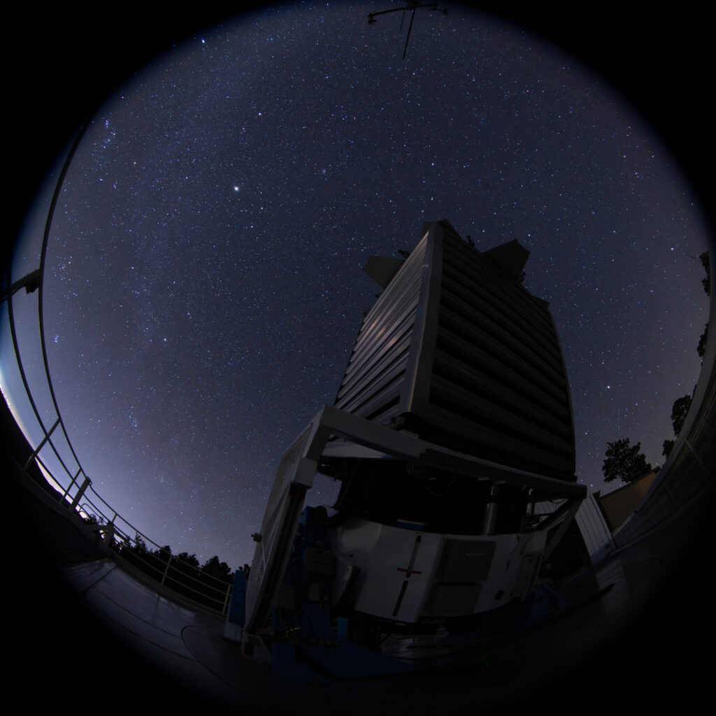 A still image from the first planetarium film showing the SDSS telescope observing under dark skies.